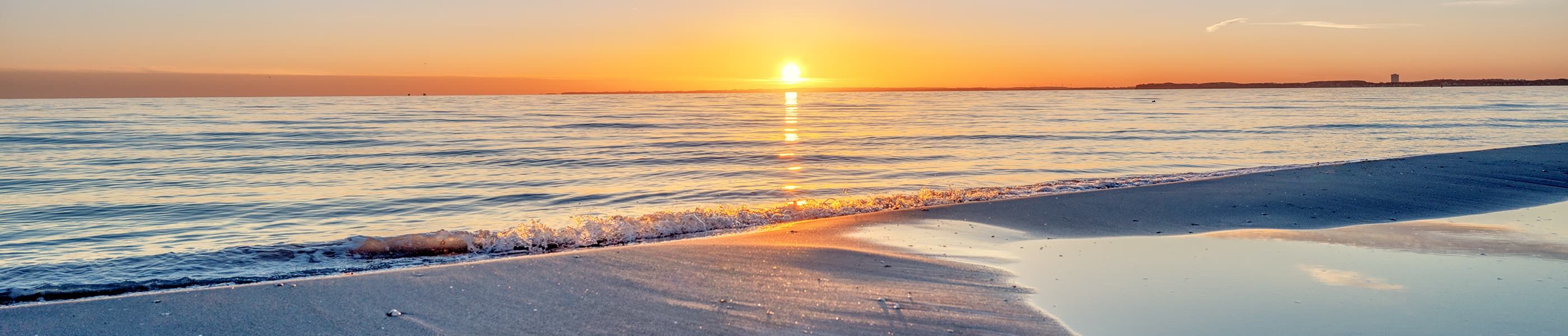 Helles Design-Wohnzimmer einer Ferienwohnung in Scharbeutz mit Lounge-Sofa und Balkon – exklusive Ausstattung an der Ostsee